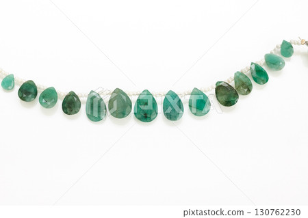 Emerald briolette bead strands and tassels against a white background 130762230