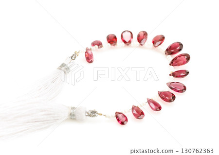 Rhodolite garnet briolette bead strands lined up on white background 130762363