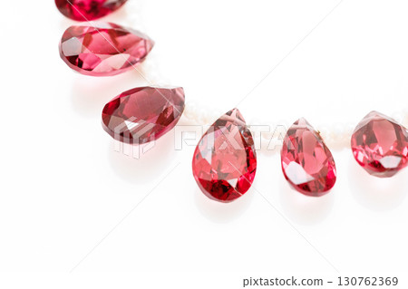 Rhodolite garnet briolette bead strands lined up on white background 130762369