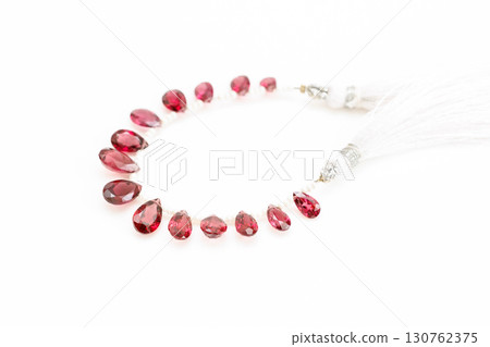 Rhodolite garnet briolette bead strands lined up on white background 130762375