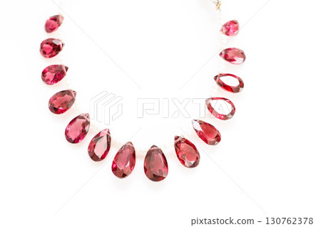 Rhodolite garnet briolette bead strands lined up on white background Rhodolite garnet briolette bead strands lined up on white background 130762378