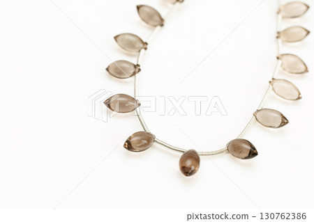Smoky quartz marquise cut bead strands arranged on a white background 130762386