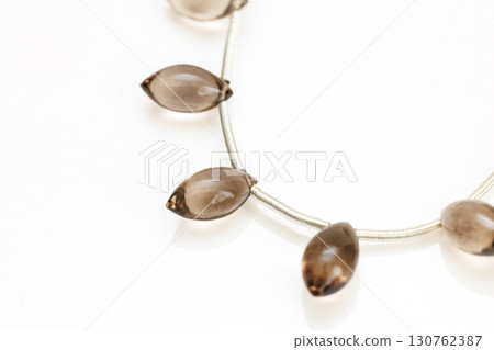 Smoky quartz marquise cut bead strands arranged on a white background 130762387