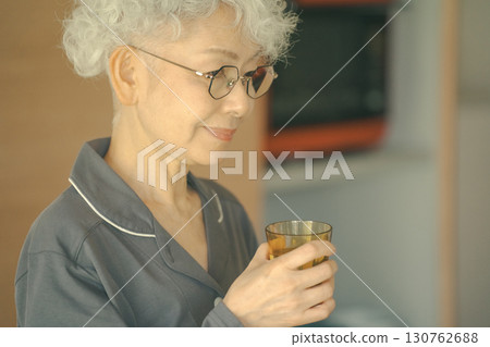 Elderly people drinking water in the kitchen as soon as they wake up 130762688
