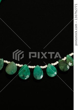 Briolette cut loose emerald and pearls that stand out against a black background 130762771