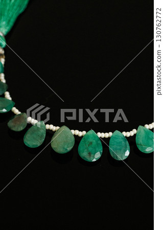 Briolette cut loose emerald and pearls that stand out against a black background 130762772