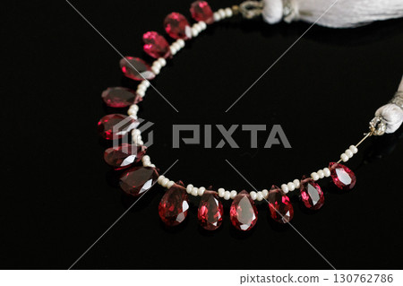 Rhodolite garnet and pearl briolette cut loose stones that stand out against a black background Rhodolite garnet and pearl briolette cut loose stones that stand out against a black background 130762786