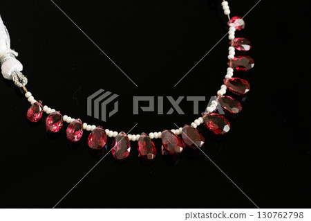 Rhodolite garnet and pearl briolette cut loose stones that stand out against a black background 130762798