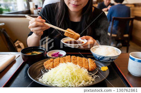 A woman eating a pork cutlet set meal 130762861