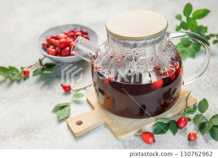 Steaming rosehip tea brewing in glass teapot on wooden board Steaming rosehip tea brewing in glass teapot on wooden board 130762962