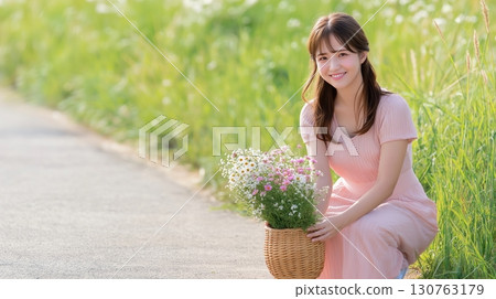 A woman squatting on the roadside picking flowers into a basket 130763179