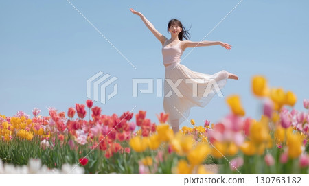 A woman jumps like she's dancing ballet in a colorful tulip field 130763182