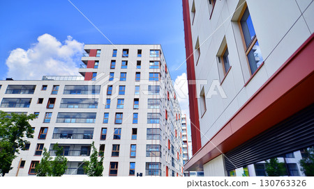 Exterior of a high modern multi-story apartment building - facade, windows and balconies. Timeless glass facade. Modern urban living district. 130763326