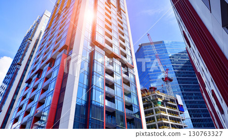Exterior of a high modern multi-story apartment building - facade, windows and balconies. Timeless glass facade. Modern urban living district. 130763327