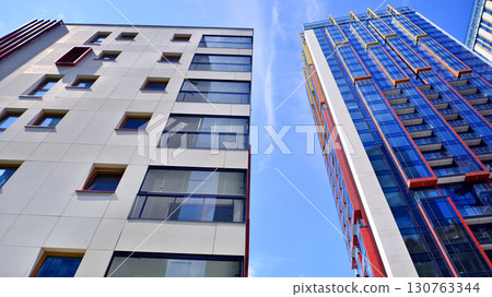 Exterior of a high modern multi-story apartment building - facade, windows and balconies. Timeless glass facade. Modern urban living district. 130763344