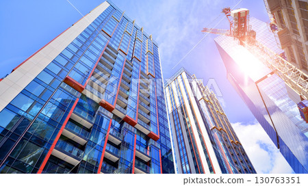 Exterior of a high modern multi-story apartment building - facade, windows and balconies. Timeless glass facade. Modern urban living district. 130763351
