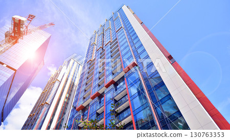 Exterior of a high modern multi-story apartment building - facade, windows and balconies. Timeless glass facade. Modern urban living district. 130763353