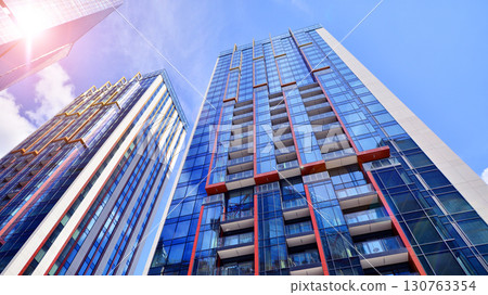Exterior of a high modern multi-story apartment building - facade, windows and balconies. Timeless glass facade. Modern urban living district. 130763354