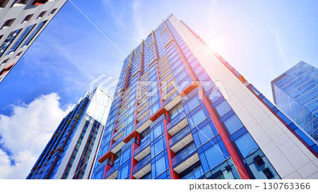 Exterior of a high modern multi-story apartment building - facade, windows and balconies. Timeless glass facade. Modern urban living district. 130763366