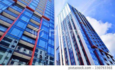 Exterior of a high modern multi-story apartment building - facade, windows and balconies. Timeless glass facade. Modern urban living district. 130763368