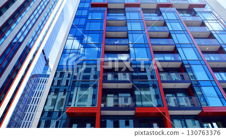 Exterior of a high modern multi-story apartment building - facade, windows and balconies. Timeless glass facade. Modern urban living district. Exterior of a high modern multi-story apartment building - facade, windows and balconies. Timeless glass facade. Modern urban living district. 130763376