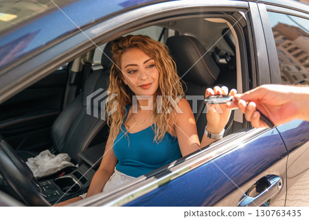 Happy Woman Receiving Car Keys Through Vehicle Window 130763435