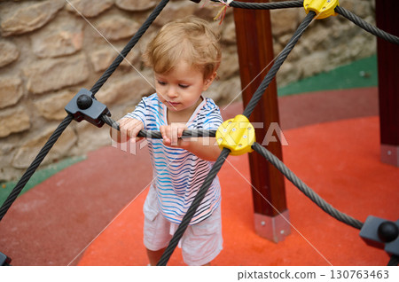 Child Playing on Rope Structure at Outdoor Playground Child Playing on Rope Structure at Outdoor Playground 130763463