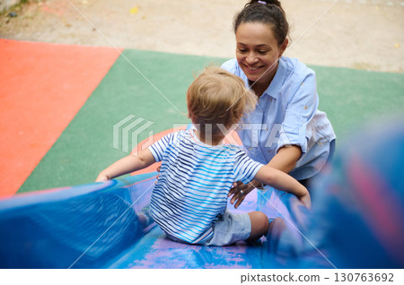 Mother Sharing a Fun Moment With Her Toddler at Playground Slide Mother Sharing a Fun Moment With Her Toddler at Playground Slide 130763692
