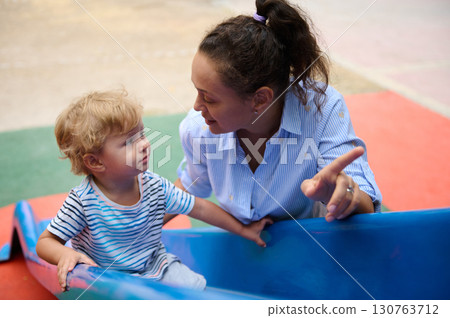 Mother Sharing a Special Moment with Child at a Colorful Playground Mother Sharing a Special Moment with Child at a Colorful Playground 130763712