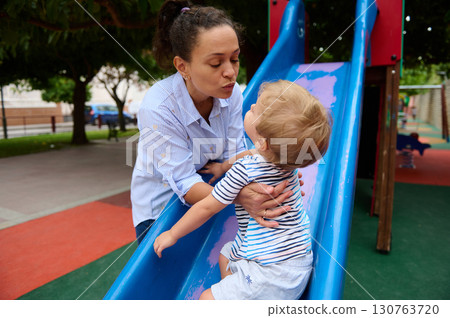 Mother and Child Playing Together at the Playground Slide Outdoors 130763720