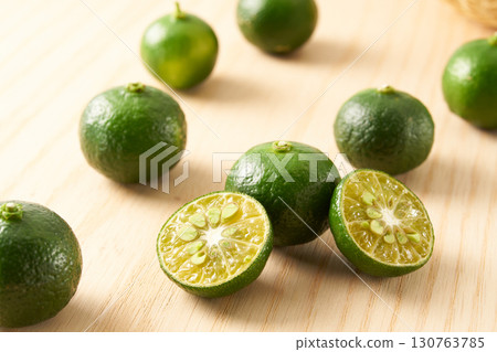 Green sliced Shikuwasa on a wood grain background Green sliced Shikuwasa on a wood grain background 130763785