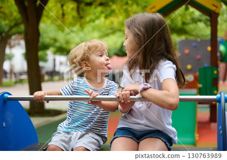 Playful Siblings Sharing Laughter and Fun at a Colorful Park Playground 130763989
