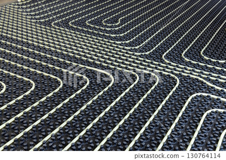 Plastic pipes for underfloor heating system installed over black insulation sheets in a new building 130764114