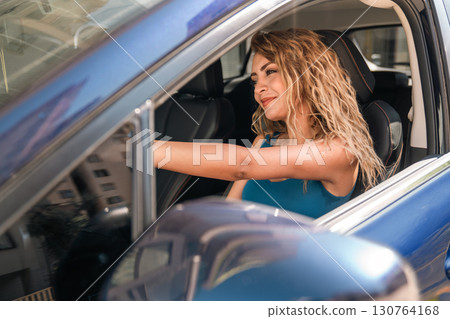 Young Blonde Woman Enjoying and Smiling in Blue Car 130764168