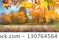 colorful fall leaves on wooden floor, blurred autumn natural background of forest with maple trees 130764564