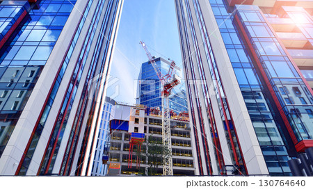 Crane on the construction site in a site surrounded by the high buildings. Office building under construction in the vicinity of high apartment buildings and office building. 130764640