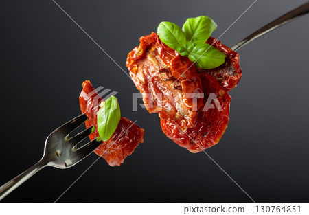 Sun dried tomatoes in olive oil with green basil. 130764851