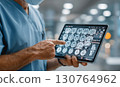 Medical doctor wearing surgical mask analyzing brain mri scan images on tablet computer 130764962