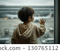 Toddler watching airplane taking off from airport window on rainy day 130765112