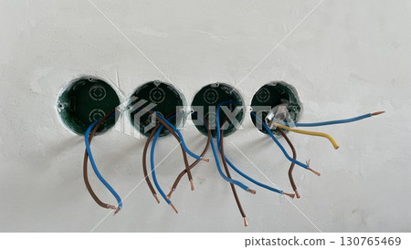 Electrical wiring installation in wall sockets. Exposed copper wires with plastic insulation for electricity connection in building construction Power supply system, safety, repair, renovation concept 130765469