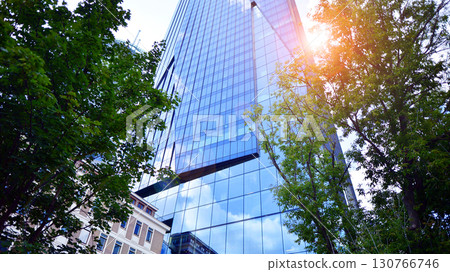 Sustainable glass office building with trees for reducing carbon dioxide. Eco-friendly building in modern city. Office with green environment. Corporate building reduce CO2. 130766746