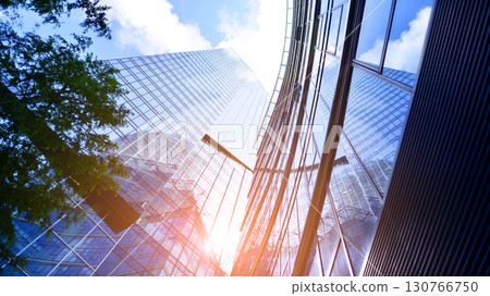 Sustainable glass office building with trees for reducing carbon dioxide. Eco-friendly building in modern city. Office with green environment. Corporate building reduce CO2. Sustainable glass office building with trees for reducing carbon dioxide. Eco-friendly building in modern city. Office with green environment. Corporate building reduce CO2. 130766750