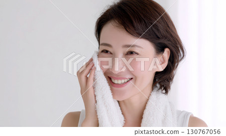 A woman wiping his face with a towel 130767056