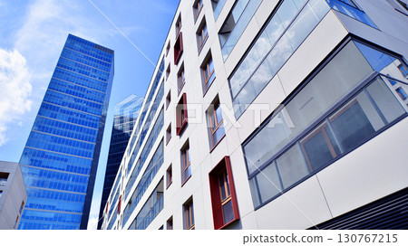 View of an modern apartment building standing next to a new modern office building with a glass facade. 130767215
