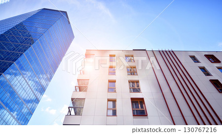 View of an modern apartment building standing next to a new modern office building with a glass facade. 130767216
