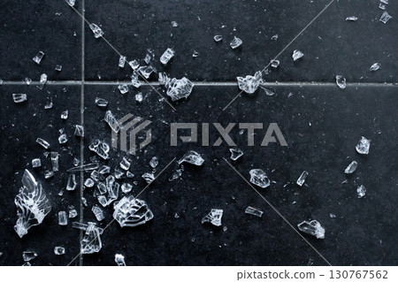 Broken glass pieces scattered on dark floor tiles Broken glass pieces scattered on dark floor tiles 130767562