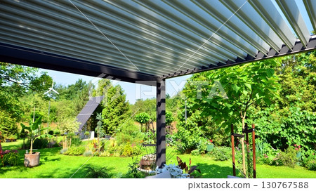 Modern aluminum pergola with stylish garden furniture in a beautiful garden. 130767588