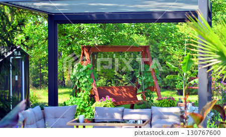 Modern aluminum pergola with stylish garden furniture in a beautiful garden. Modern aluminum pergola with stylish garden furniture in a beautiful garden. 130767600