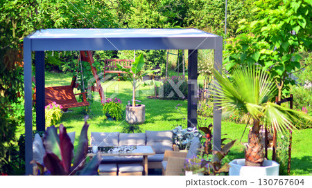 Modern aluminum pergola with stylish garden furniture in a beautiful garden. Modern aluminum pergola with stylish garden furniture in a beautiful garden. 130767604