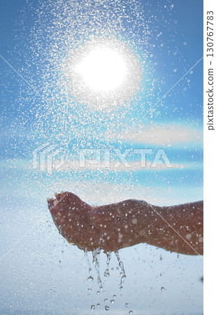 Hand catching water droplets under bright summer sun Hand catching water droplets under bright summer sun 130767783